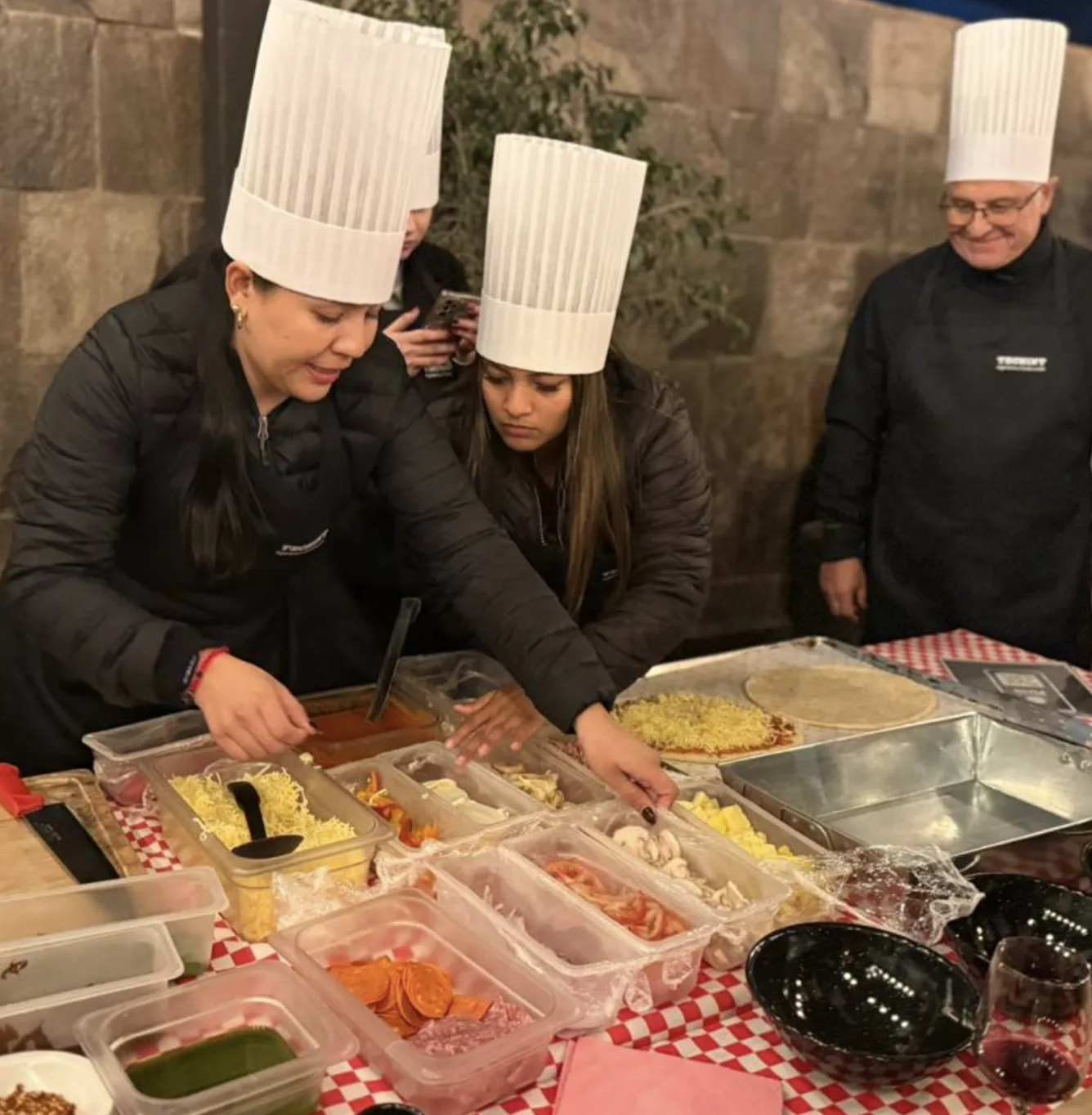 Equipo con gorros de chef prepara pizzas en la experiencia gastronómica Iron Chef de TEAMS en Monterrey